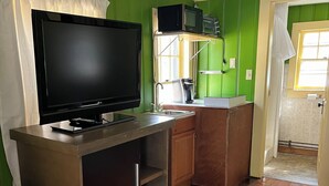 Una cocina compacta con televisor de pantalla plana, microondas y cafetera.