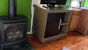 Una cocina con estufa de leña, televisor de pantalla plana y muebles de madera.