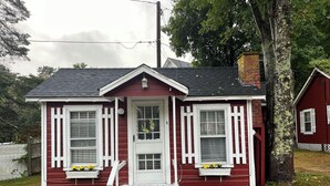 Una casa roja con detalles blancos, un porche y una chimenea.