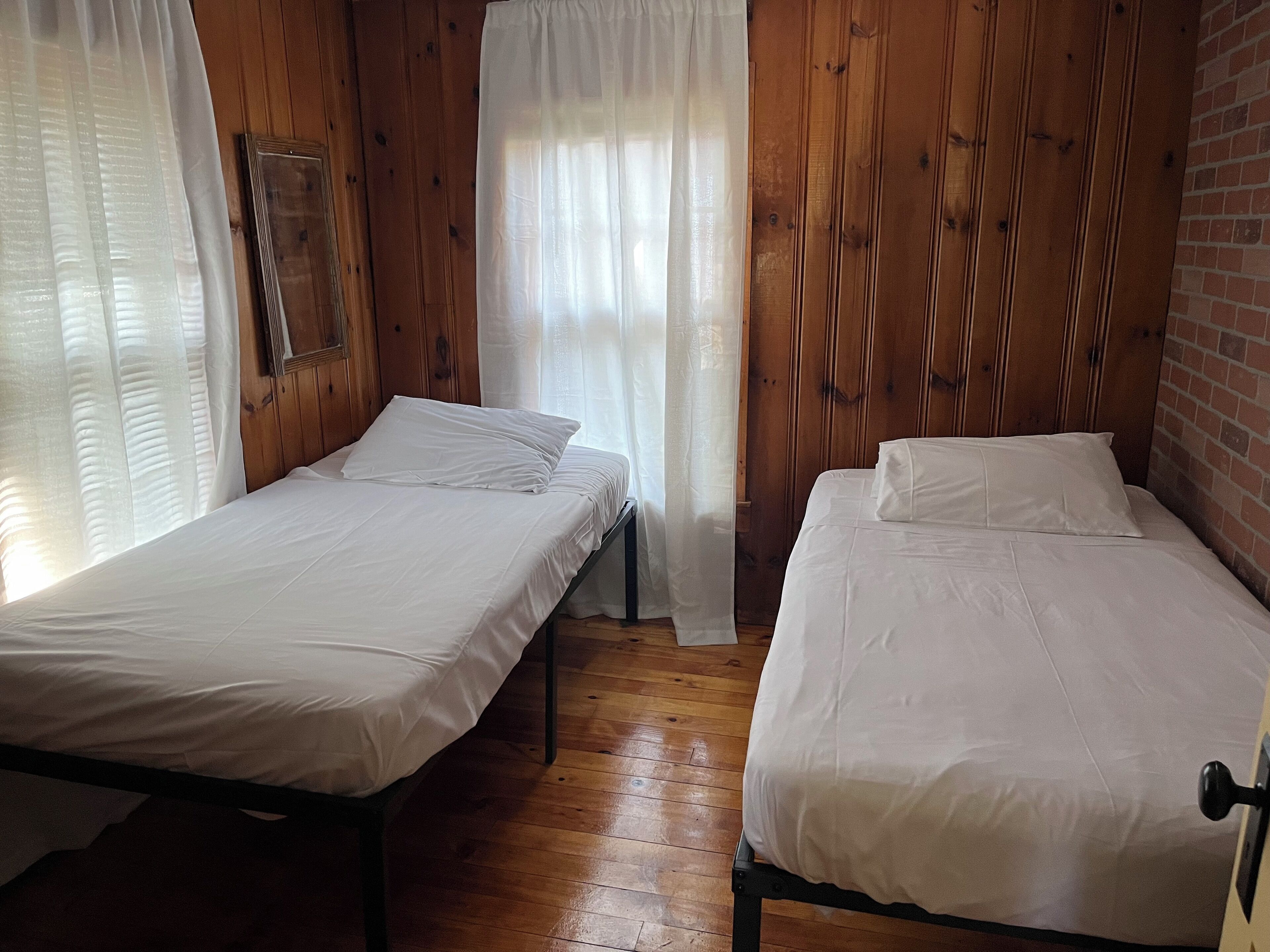 Due letti singoli in una stanza con pareti e pavimento in legno.