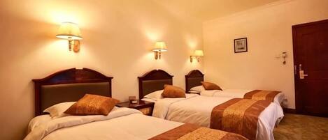 Une chambre d’hôtel avec trois lits, chacun doté d’une tête de lit et de lampes de chevet.