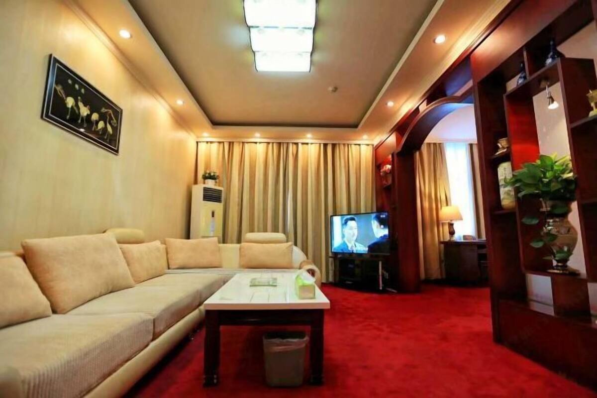 Una sala de estar con un sofá, televisor y una alfombra roja.