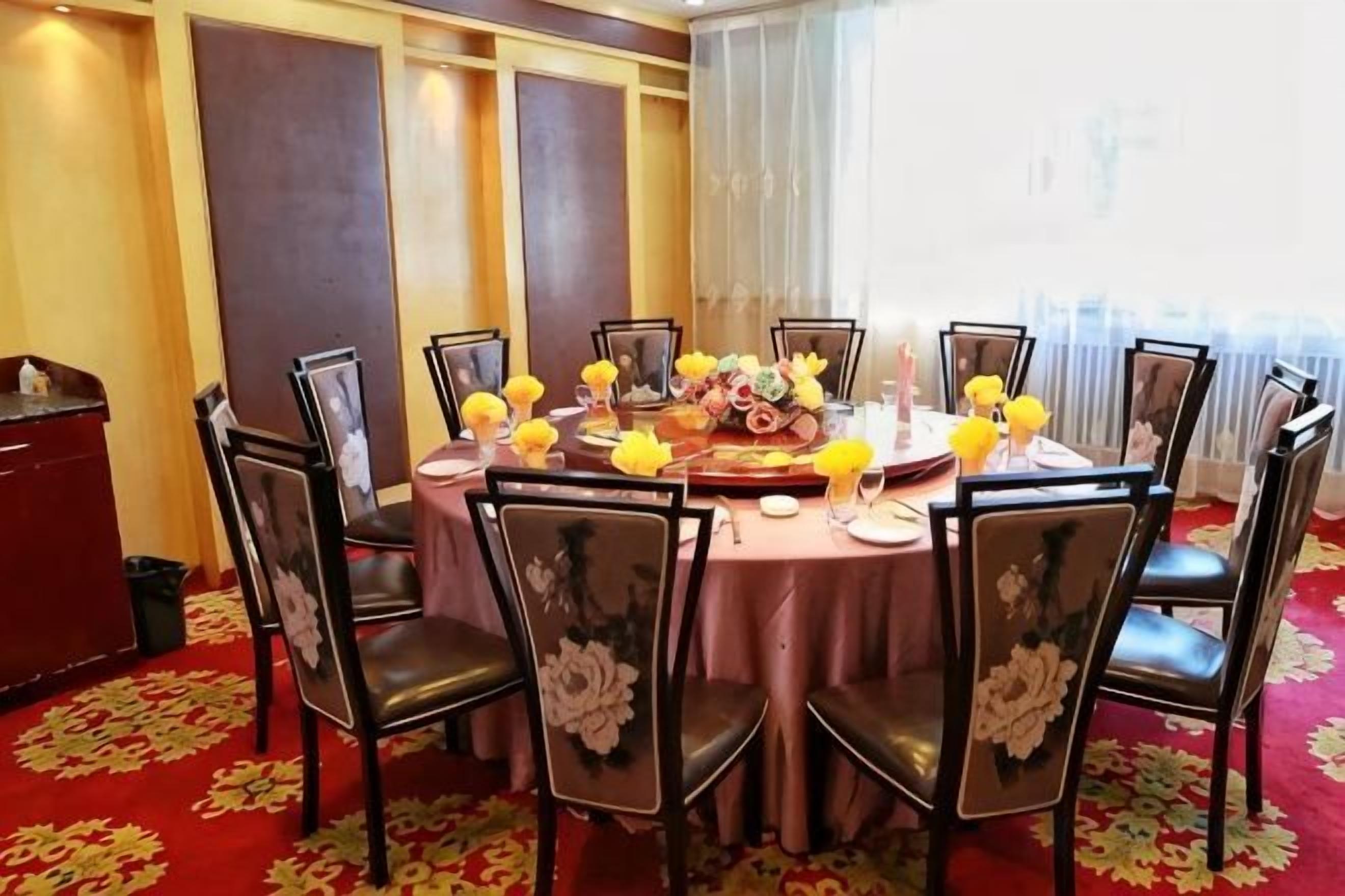 Un tavolo rotondo da pranzo con otto sedie, ciascuna decorata con un motivo floreale, apparecchiato con fiori gialli e un centrotavola.