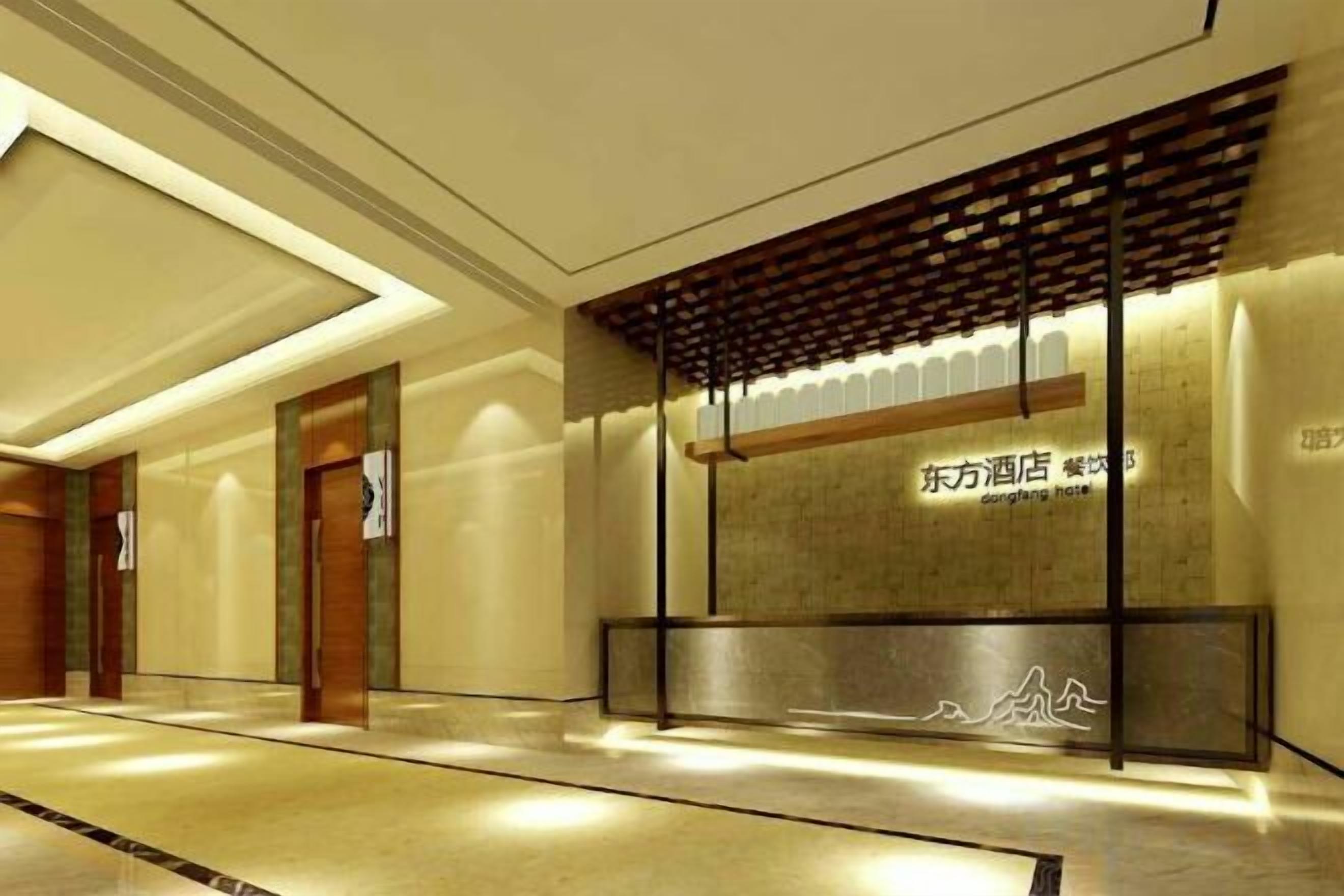 A hotel reception area with a modern design, featuring a reception desk, a wall with signage, and a patterned floor.