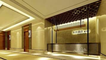 A hotel reception area with a modern design, featuring a reception desk, a wall with signage, and a patterned floor.