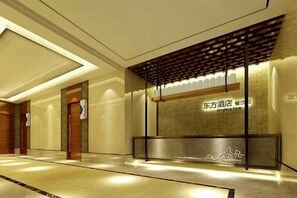 Zona de recepción de hotel con diseño moderno, que incluye un mostrador de recepción, una pared con señalización y un suelo con diseño.