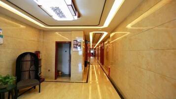 Un pasillo de hotel con piso de mármol, un mostrador de recepción y una puerta que da a otra habitación.