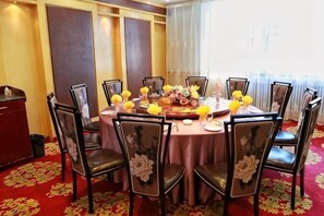 A round dining table with chairs, a floral centerpiece, and a red carpet.