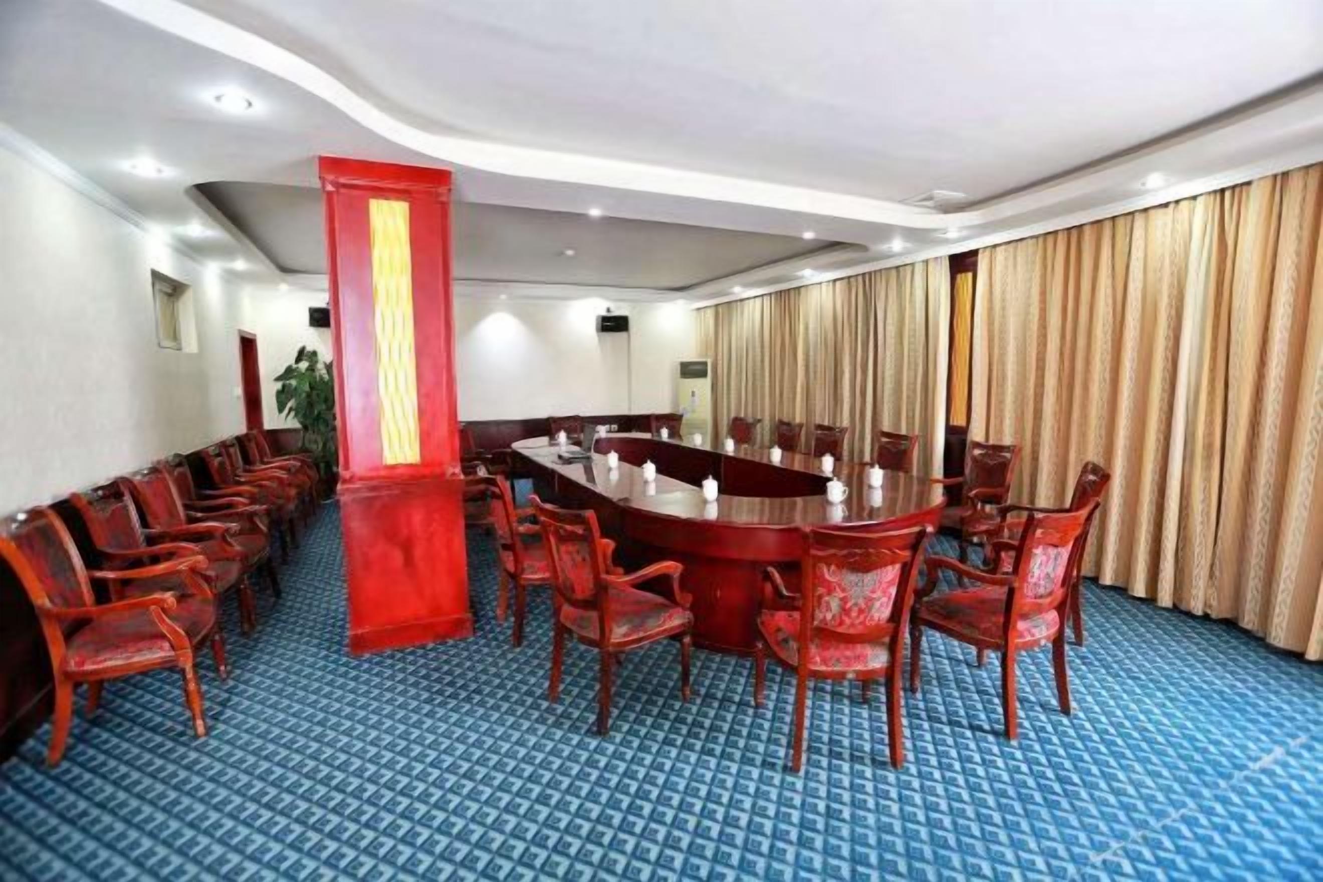A conference room with a long table, multiple chairs, and a blue carpeted floor.