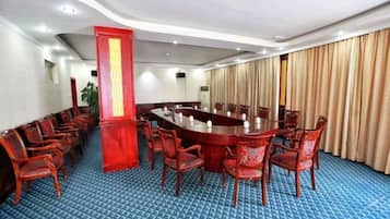 A conference room with a long table, multiple chairs, and a blue carpeted floor.