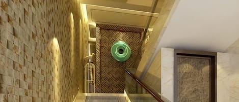 A staircase with a patterned wall, a handrail, and a door at the bottom.