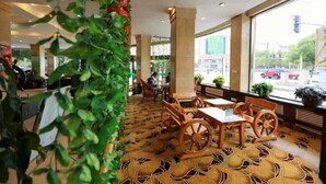 Een restaurant met houten tafels en stoelen, grote ramen met uitzicht op de straat en een vloer met patroon.