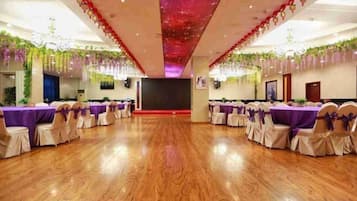 A banquet hall with round tables, chairs, and a stage.