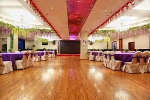 A banquet hall with round tables, chairs, and a stage. - Dong Fang Hotel (Jiayuguan)