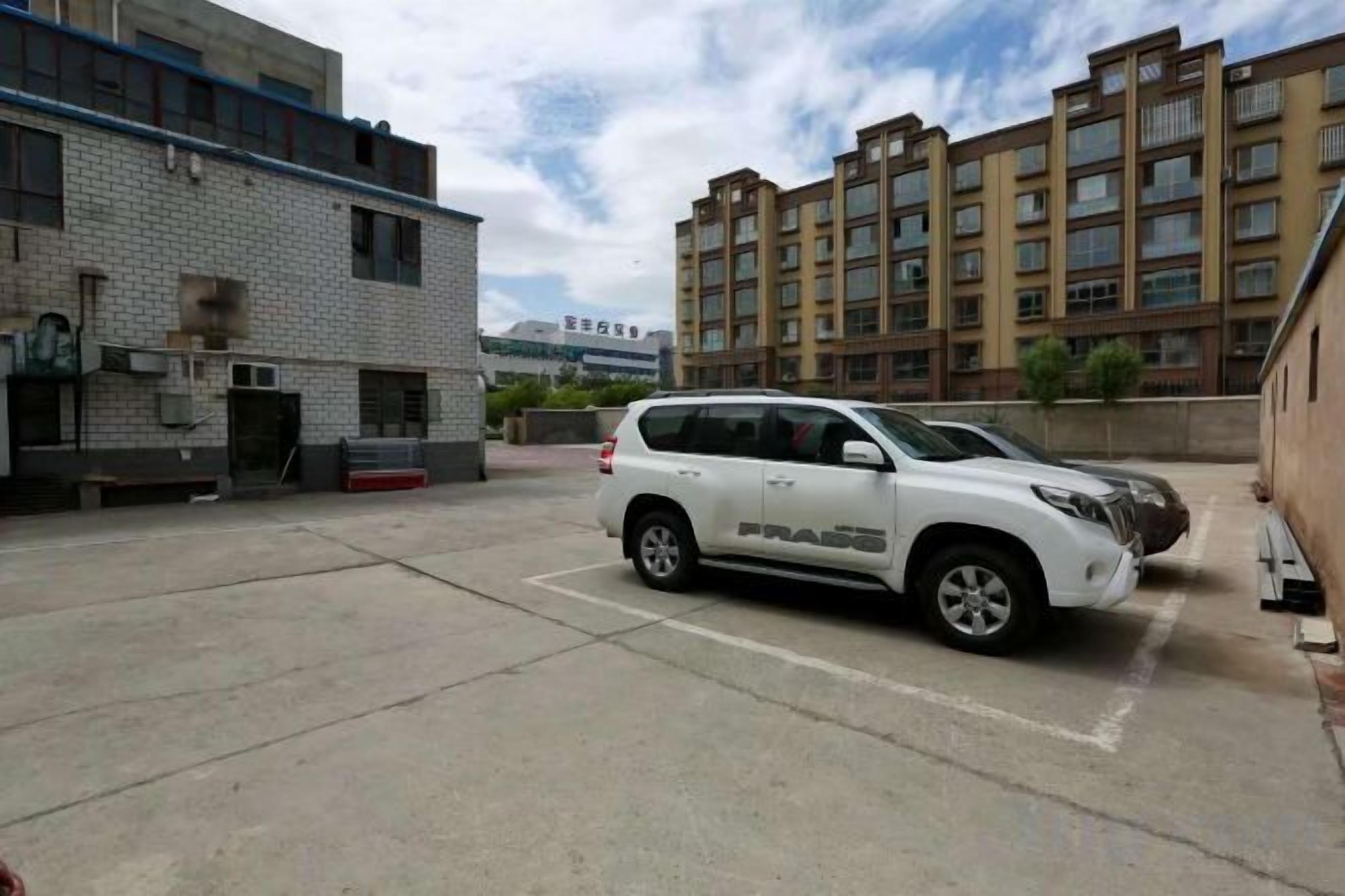 Un estacionamiento con un SUV blanco estacionado al frente.