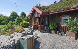 A wooden cabin with a porch, outdoor seating, and a gravel driveway. - Nice home in Farstad with WiFi (Farstad)