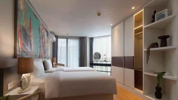 A modern hotel room with a large bed, a desk, and a bookshelf. - Beachwalk Residence (Bali)
