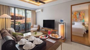 A modern hotel room with a sofa, dining table, TV, and a balcony with outdoor seating. - Beachwalk Residence (Bali)