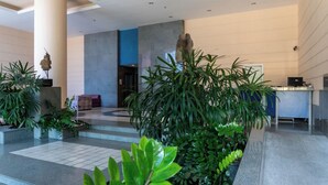 Un hall d’entrée moderne comprenant un comptoir d’accueil, un escalier et diverses plantes d’intérieur.