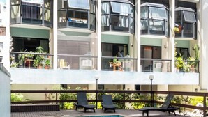 Un hôtel à plusieurs étages doté d’une piscine, d’un espace extérieur aménagé et de balcons ornés de plantes.