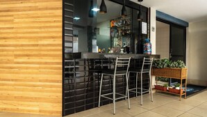 Une cuisine moderne avec un revêtement mural noir, un coin bar avec des tabourets et une petite table d’appoint agrémentée de plantes.