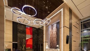 Eine moderne Hotelhalle mit Rezeption, einer Sitzecke und einem großen, abstrakten Wandbild.