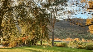 Un parque con césped, árboles y una cadena montañosa a lo lejos.