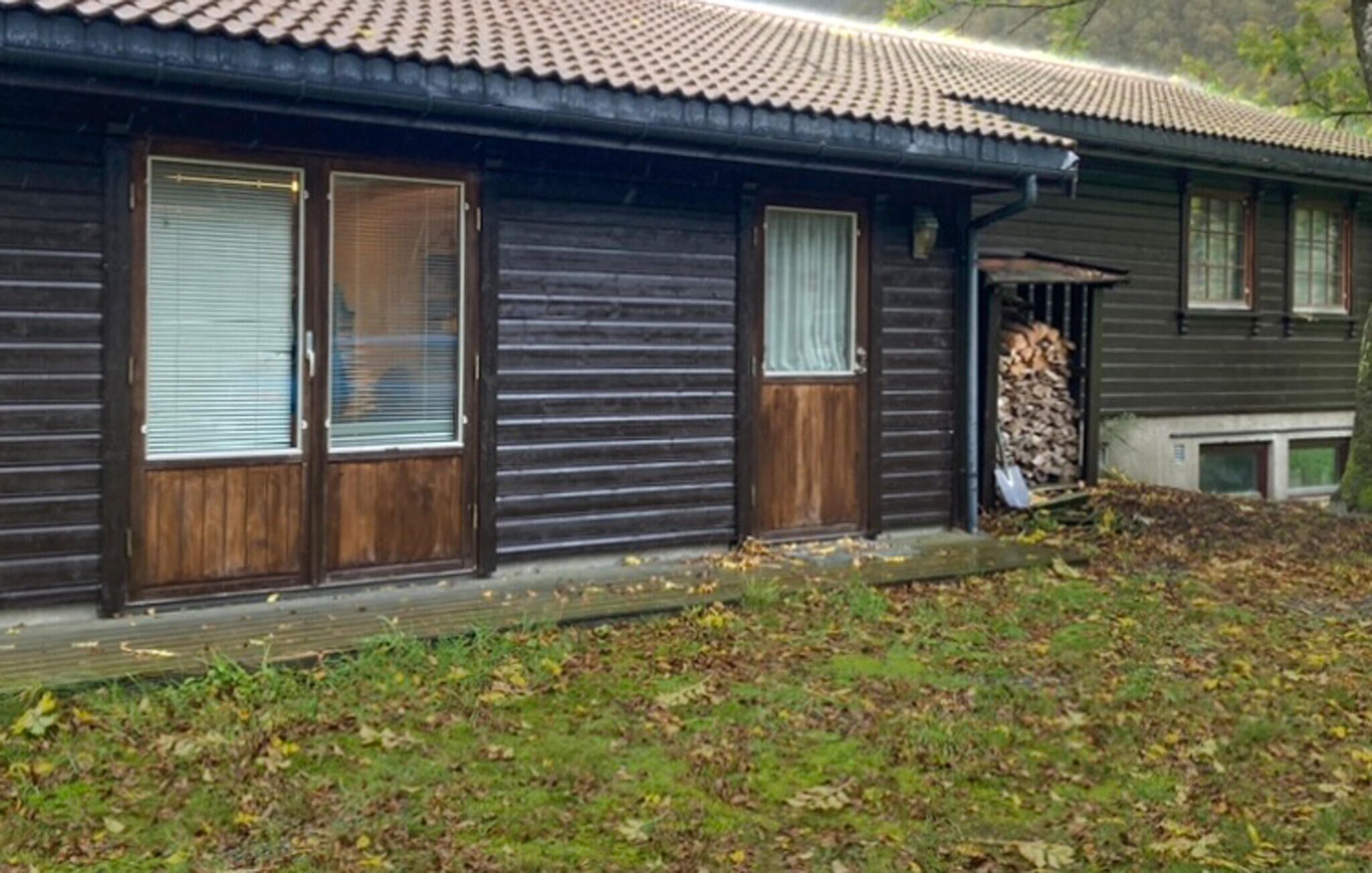 A traditional wooden house with a tiled roof, large windows, and a covered porch area.