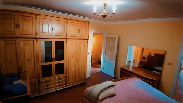 Een slaapkamer met een bed, een dressoir, een spiegel en een kledingkast.