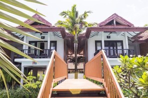A hotel with a central staircase, a palm tree, and a building with balconies. - Ramada Resort Cochin (Kochi)
