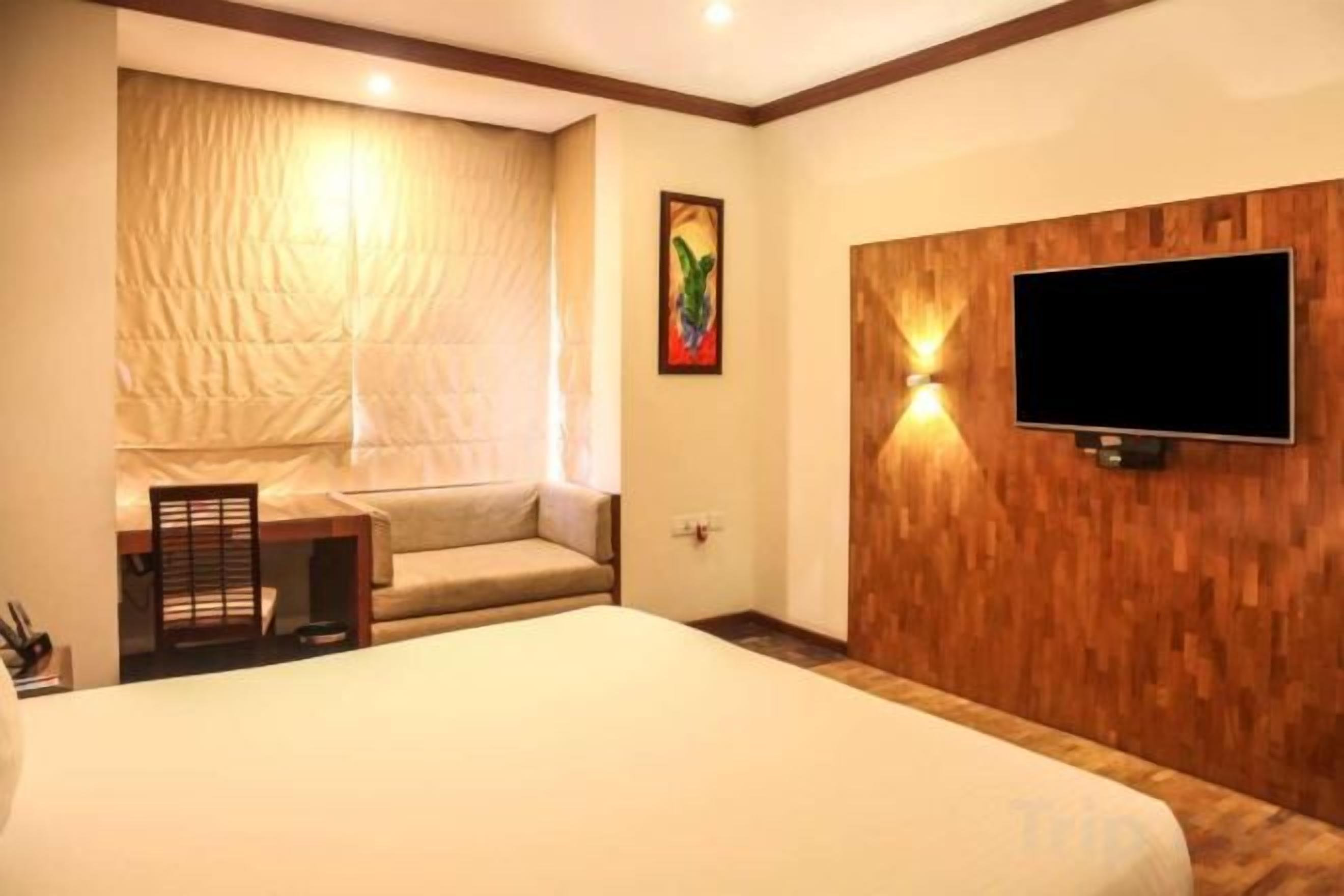 A hotel room with a large bed, a television mounted on the wall, and a small table with a chair.