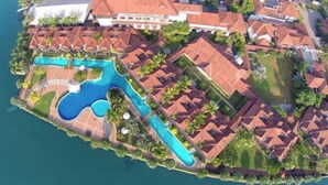 Vista aérea de un resort con varias edificaciones, una amplia piscina y zonas verdes circundantes.