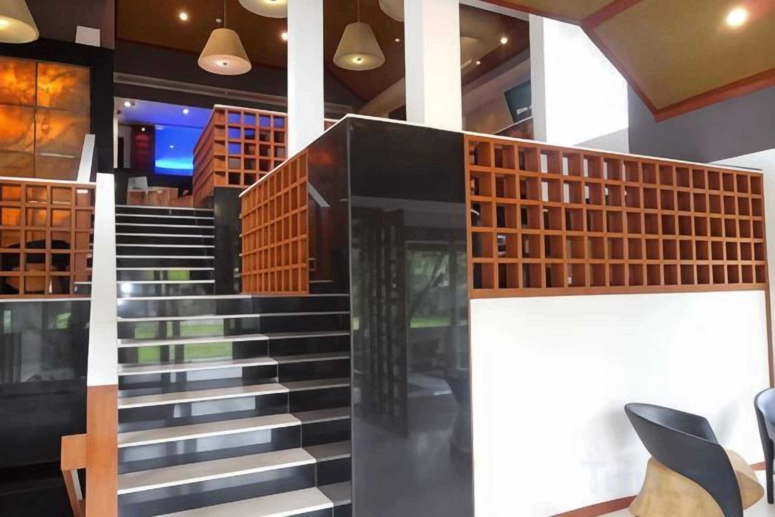 A modern staircase with a wooden railing, leading to a seating area with a chair and a table.