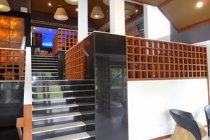 A modern staircase with a wooden railing, leading to a seating area with a chair and a table. - Ramada Resort Cochin (Kochi)