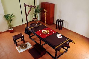 A traditional room with a long table, a bed, a cabinet, and two potted plants. - Ramada Resort Cochin (Kochi)