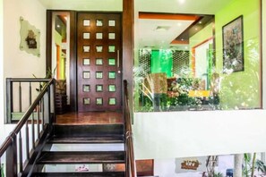 A staircase with a wooden handrail and a door with a grid pattern. - Ramada Resort Cochin (Kochi)