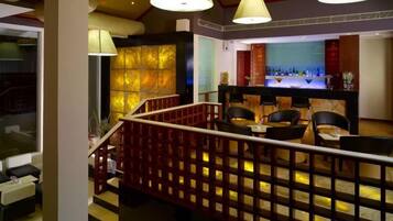 A hotel lobby with a staircase, seating area, and a bar.