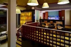 A hotel lobby with a staircase, seating area, and a bar. - Ramada Resort Cochin (Kochi)