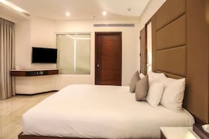 A hotel room with a large bed, a television, a wardrobe, and a mirror. - Ramada Resort Cochin (Kochi)