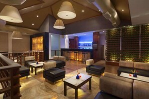 A spacious lounge area with multiple seating options, a bar, and a decorative wall. - Ramada Resort Cochin (Kochi)