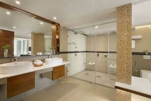 A modern bathroom with a large mirror, two sinks, a shower area, and a glass-enclosed shower stall.