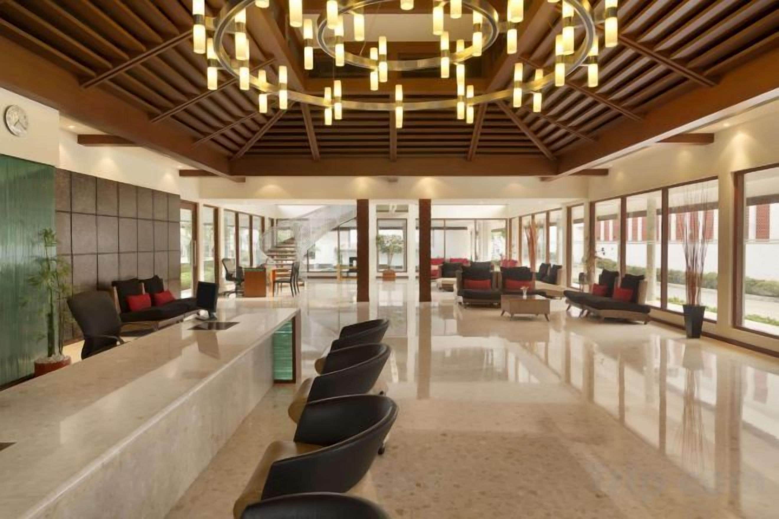 Um hall de hotel com balcão de recepção, área de estar e grandes janelas.