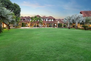 A hotel with a large lawn, multiple buildings, and palm trees. - Ramada Resort Cochin (Kochi)