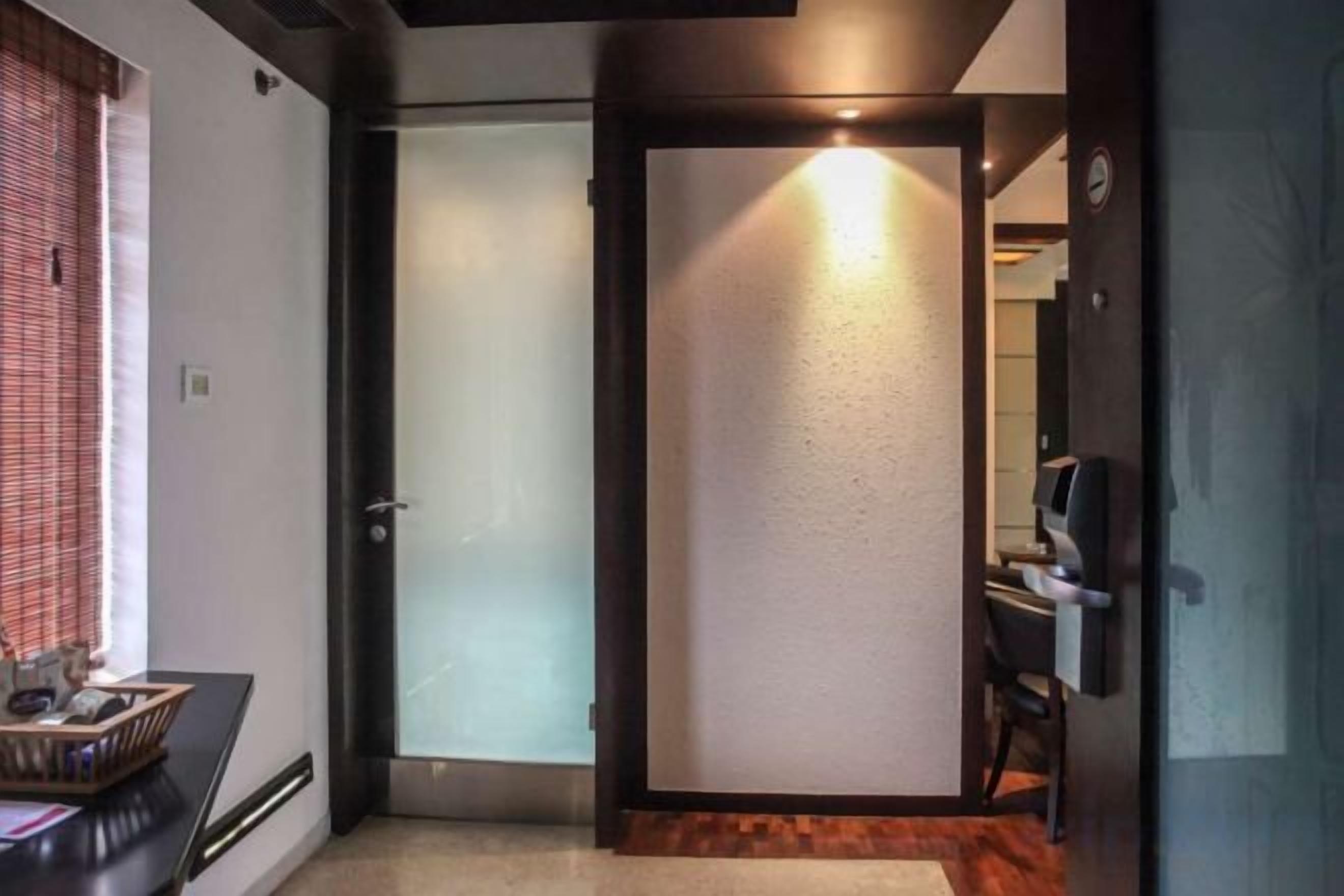 Een hotelkamer met een schuifdeur, een klein bureau met een computer en een stoel.