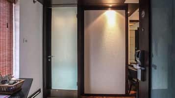 Een hotelkamer met een schuifdeur, een klein bureau met een computer en een stoel.
