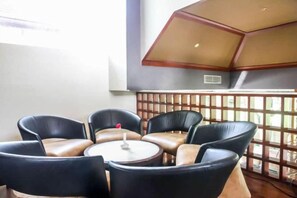 A seating area with leather chairs and a small table, a wooden partition, and a view through a lattice window. - Ramada Resort Cochin (Kochi)