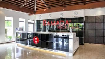 Un mostrador de recepción de diseño moderno, con un logotipo y el nombre 'RAMADA RESORT'.