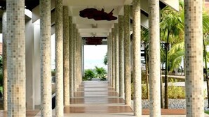 Un pasillo con columnas de baldosas y vista al mar.