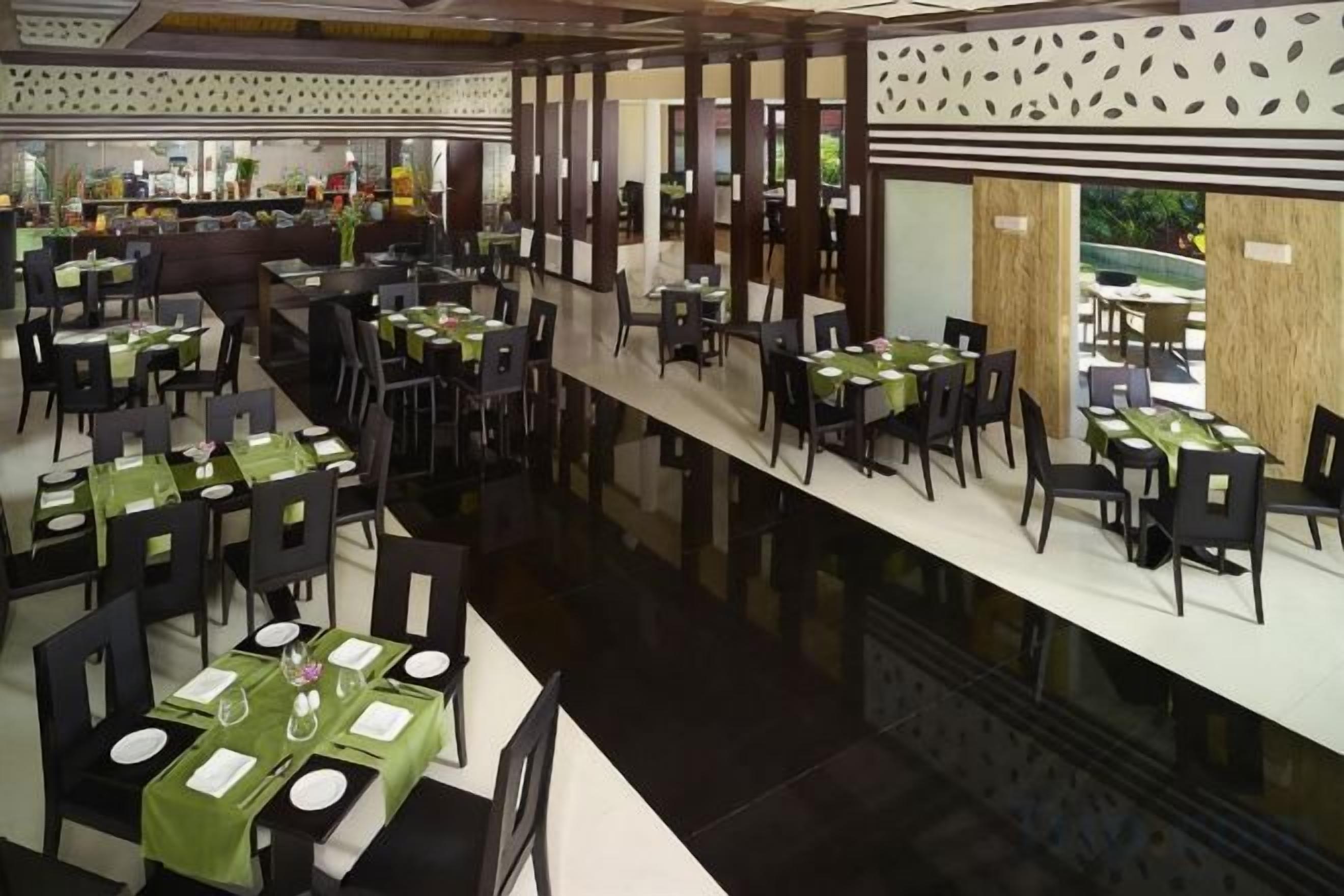 A restaurant with multiple tables and chairs, a long counter, and a view of the outdoors.
