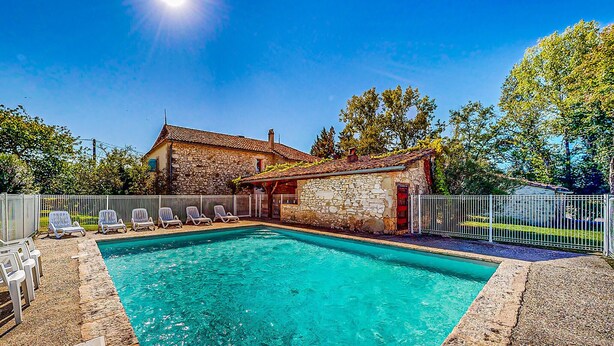 A stone house with a swimming pool, surrounded by a white fence and trees. - Presbytère de Pompiac (Castillonnès)